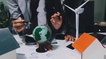 Business people working on a project with a globe and wind turbines video