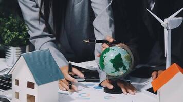 Business people working on a project with a globe and wind turbines video