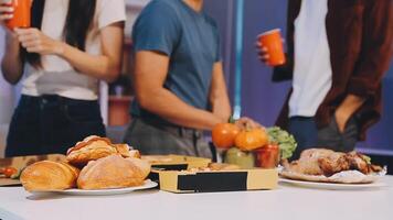 A group of people standing around a table with food video