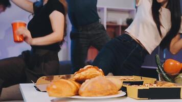 A group of people dancing around a table with pizza and drinks video