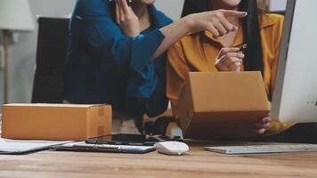 Two women are looking at a computer screen while holding boxes video