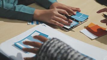 Two people working on a laptop with paper and scissors video