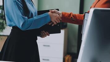 Two business people shaking hands in an office video
