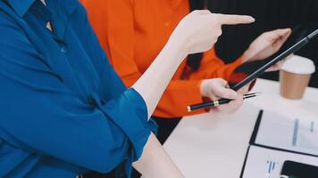 Two businesswomen are sitting at a table with a tablet video