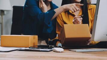 Two women are looking at a computer screen while holding boxes video