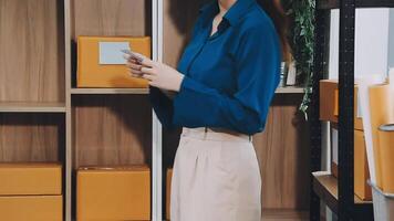 A woman in a blue shirt is standing in front of a shelf with boxes video