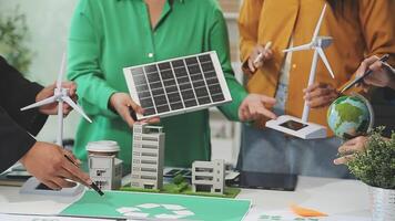 A group of people working on a project with a green building and wind turbines video