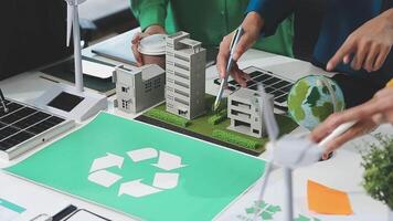 A group of people working on a table with a recycling symbol video
