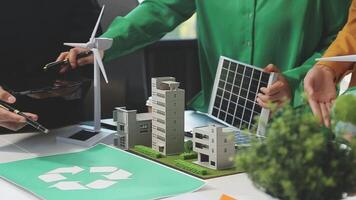 A group of people are working on a model of a building with wind turbines video