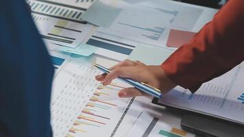A person is holding a pen and pointing to a chart video