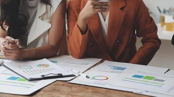 Three business people sitting at a table with papers and graphs video