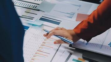 A person is holding a pen and pointing to a chart video