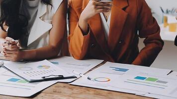 Three business people sitting at a table with papers and graphs video