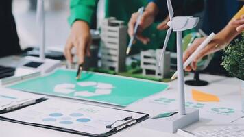People working on a project with paper and a wind turbine video