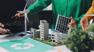 People working on a project with a model of a building and wind turbines video