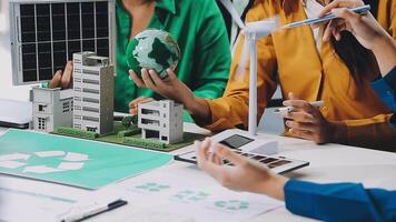 People working on a project with a model of a green building video