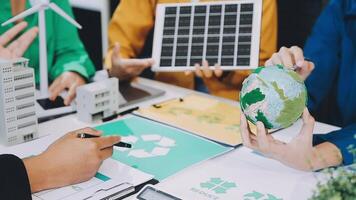 People working on a project with a green globe and a wind turbine video