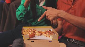 A man and woman are sitting in front of a box with pizza and chips video