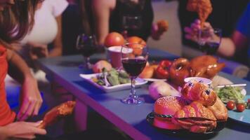 A group of people sitting at a table with food and wine video