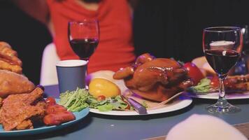 A woman is holding up a glass of wine while sitting at a table with food and drinks video