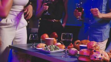 A group of people standing around a table with food and wine video