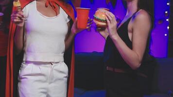 Two women dressed as superheroes holding drinks and food video