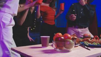 A group of people standing around a table with food video