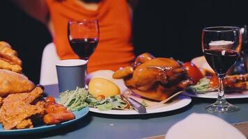 A woman is holding up a glass of wine while sitting at a table with food and drinks video