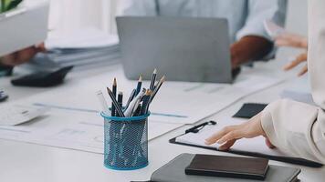 People working at a desk with pens and notebooks video