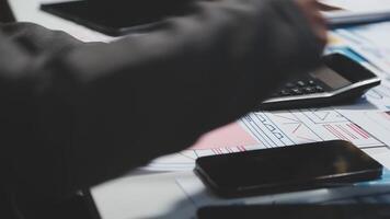 A person is using a calculator and a phone on a desk video