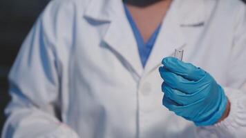 A person in a lab coat holding a small vial video