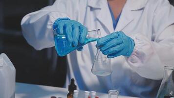 A person in a lab coat is holding a blue liquid video