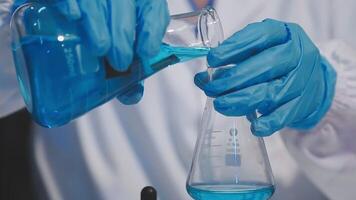 A person in a lab coat is holding a blue liquid video
