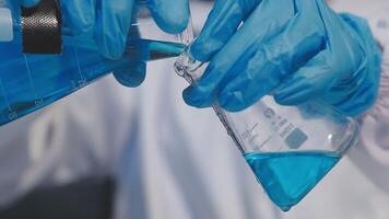 A person in a lab coat holding a blue liquid video