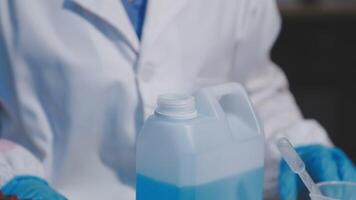 A person in a lab coat holding a container of liquid video