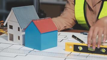 A person is working on a blueprint with a house model video