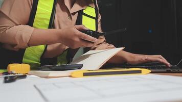 A woman in a safety vest working on a laptop video