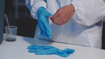 A person in a lab coat is putting on blue gloves video