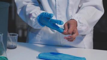 A person in a lab coat is holding a blue glove video