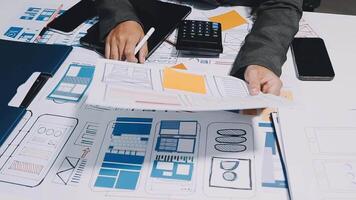 A person is working on a laptop and a paper with blueprints video