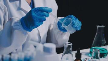 A person in a lab coat is holding a beaker video