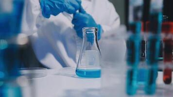 A person in a lab coat is holding a test tube video