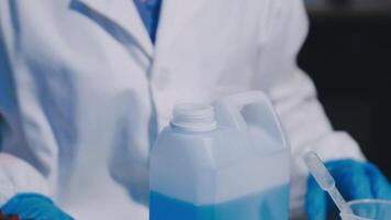 A person in a lab coat holding a container of liquid video