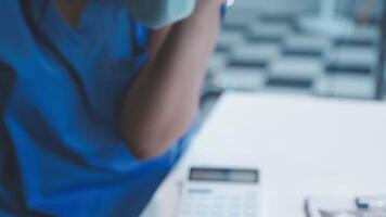 A woman in blue shirt sitting at a desk with a calculator video