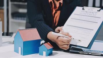 A woman signing a contract with a house model video