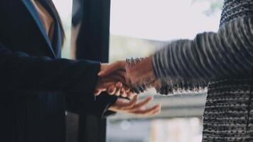 Two people shaking hands in front of a window video