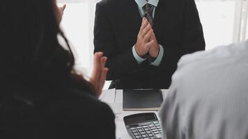 A man in a suit clapping his hands while sitting at a desk video