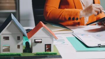 A woman is working on a house model with a tablet video