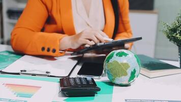 Businesswoman using calculator and globe on desk video