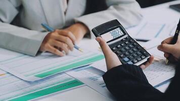 Two people are using a calculator to calculate the numbers video